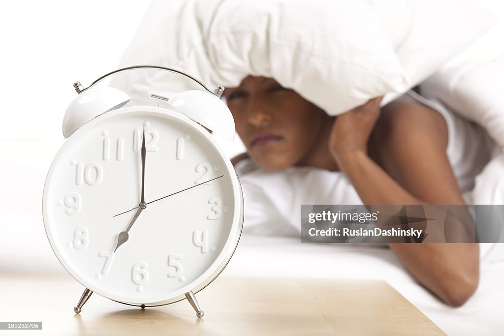 Portrait of alarm clock and upset woman in the background