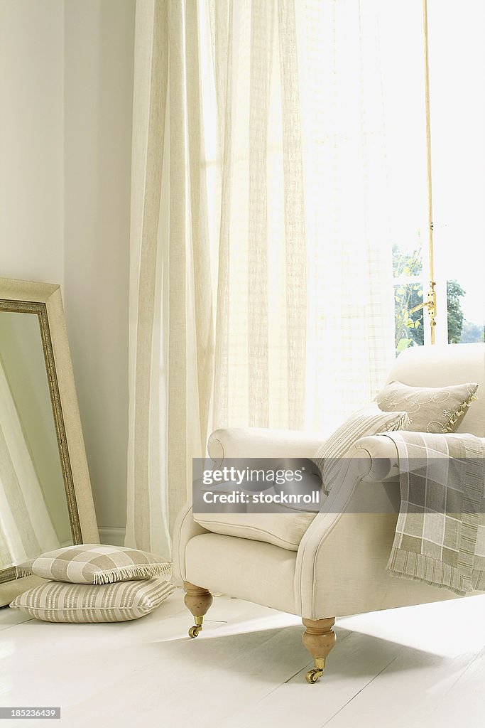 Formal white chair next to window with curtain