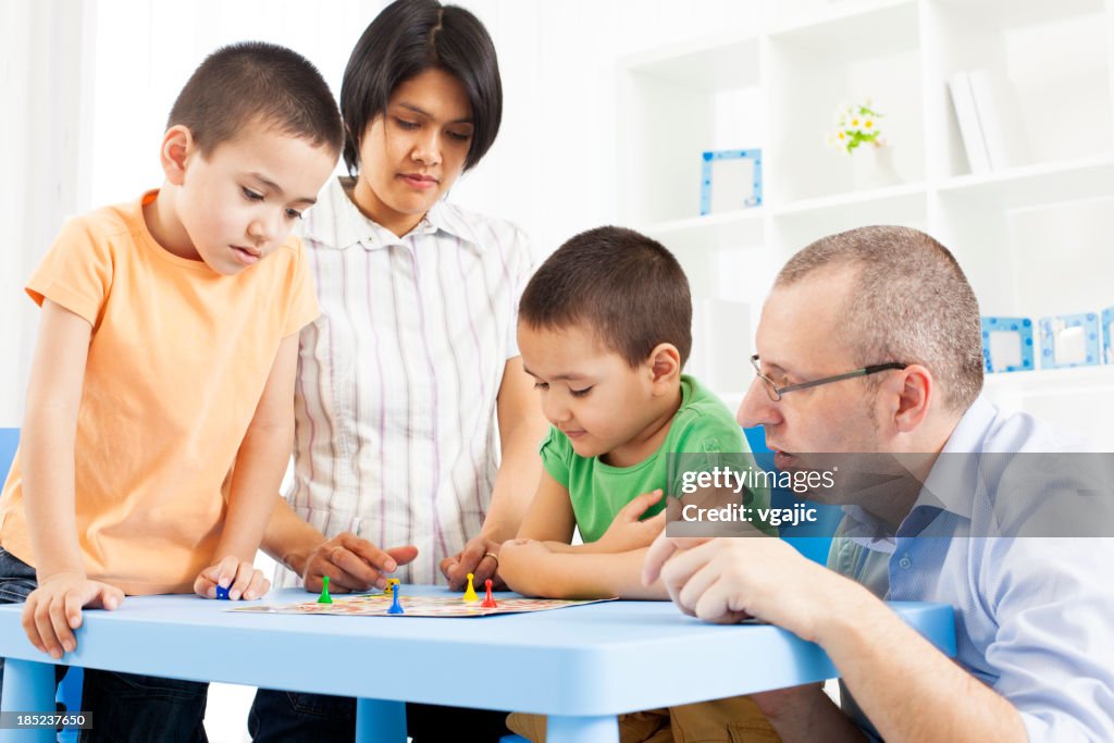 Mixed Race Family Playing Board Game.