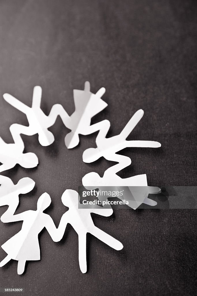 White paper chain of people in a circle on black background