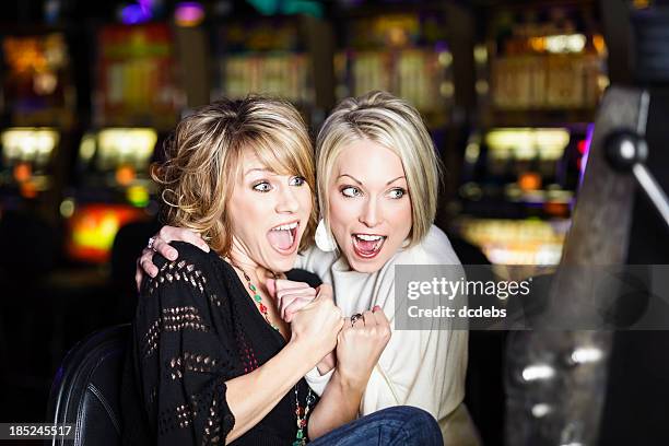 glücklich begeistert frauen preisgekrönten am spielautomaten im casino - casino win stock-fotos und bilder