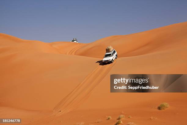 auto fahren in der wüste zwischen sanddünen - 4x4 desert stock-fotos und bilder