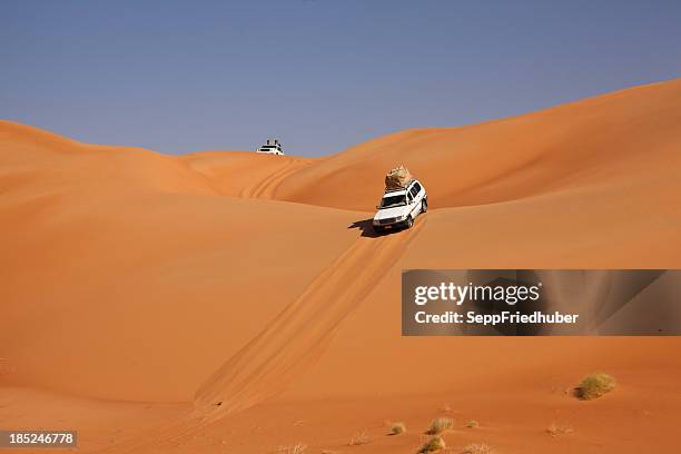 car driving in the desert between sand dunes - atv sand dune stock pictures, royalty-free photos & images