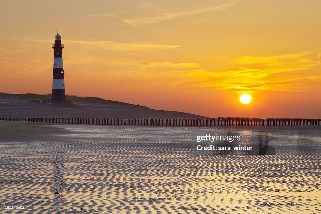 Lighthouse and beach at low tide at sunset, The Netherlands