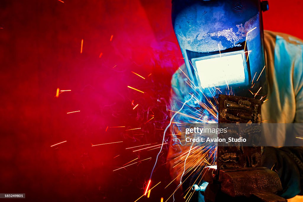 Welder welding, sparks fly.