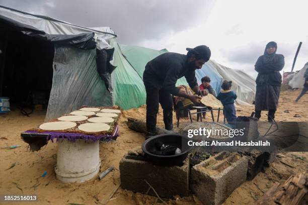 Displaced Palestinians are pictured cooking meals by their makeshift tents on December 13, 2023 in Al-Mawasi, Rafah, Gaza. A so-called safe zone...