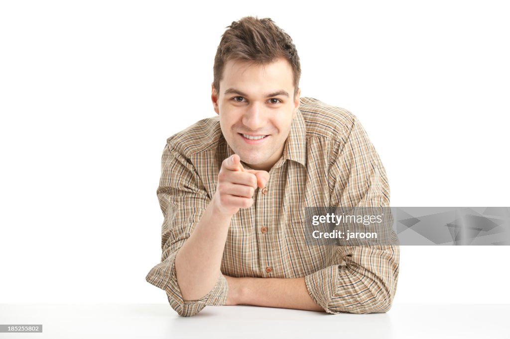 Happy young handsome man sitting and pointing