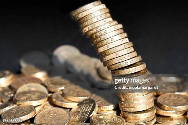 stack of one pound coins falling over - british currency stockfoto's en -beelden