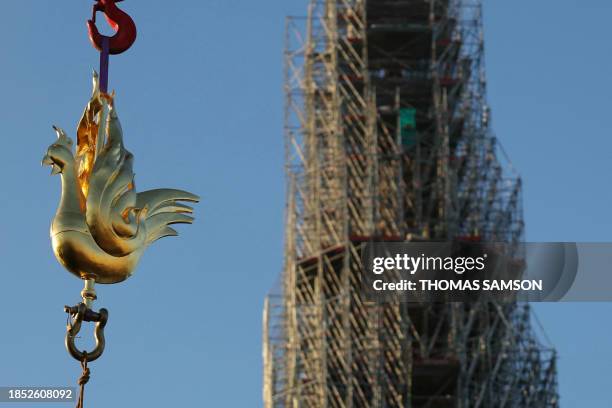 The new golden rooster containing relics is lifted by crane to be installed atop the spire of Notre Dame cathedral as part of its reconstruction, in...