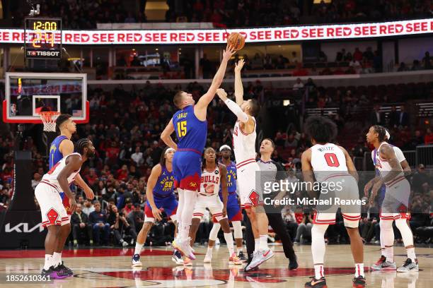 Nikola Jokic of the Denver Nuggets and Nikola Vucevic of the Chicago Bulls tip-off the game at the United Center on December 12, 2023 in Chicago,...