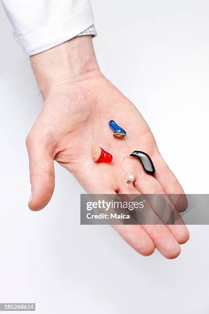 tiny hearing aids on doctor's hand - small hearing aids stock pictures, royalty-free photos & images