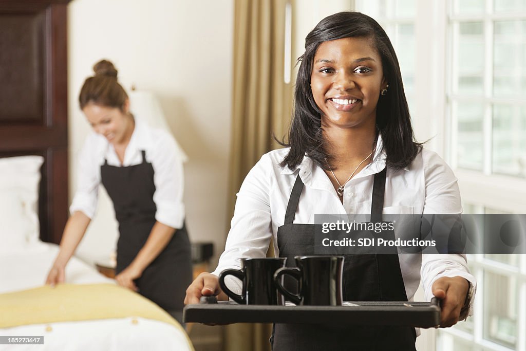 Hotel room service lady offering coffee on tray