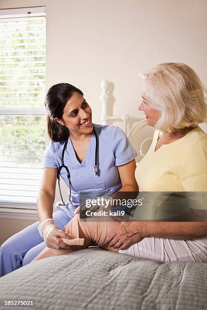 healthcare worker bandaging patient's knee - bandage stockfoto's en -beelden