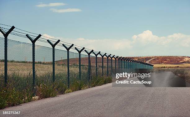 road next to a fence - grens stockfoto's en -beelden