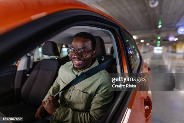 photo of a black man sitting in the car and putting on his seat belt - car man stock pictures, royalty-free photos & images