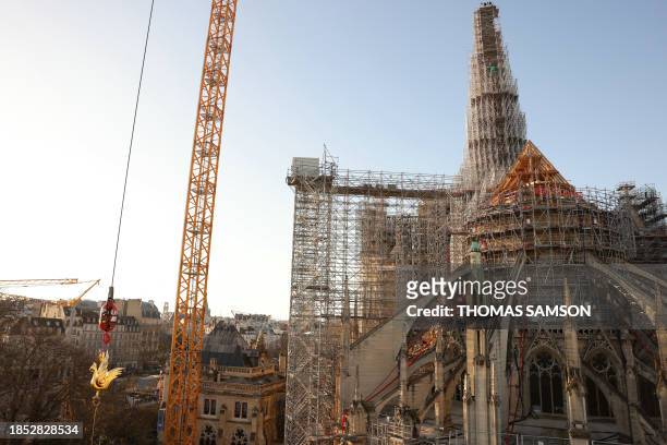 The new golden rooster containing relics is lifted by crane to be installed atop the spire of Notre Dame cathedral as part of its reconstruction, in...