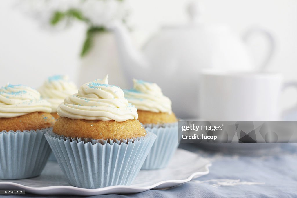 Bleu cupcakes vanille avec glaçage et théière et tasses en arrière-plan