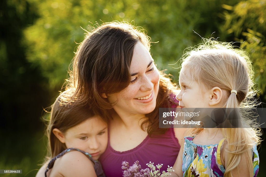 Glückliche Mutter und zwei Töchter sitzen zusammen
