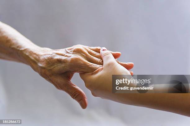 young hand reaching out to a elderly persons hand - respect word stock pictures, royalty-free photos & images