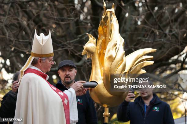 Archbishop of Paris Laurent Ulrich places relics inside the new golden rooster during its blessing and prior to its installation atop the spire of...