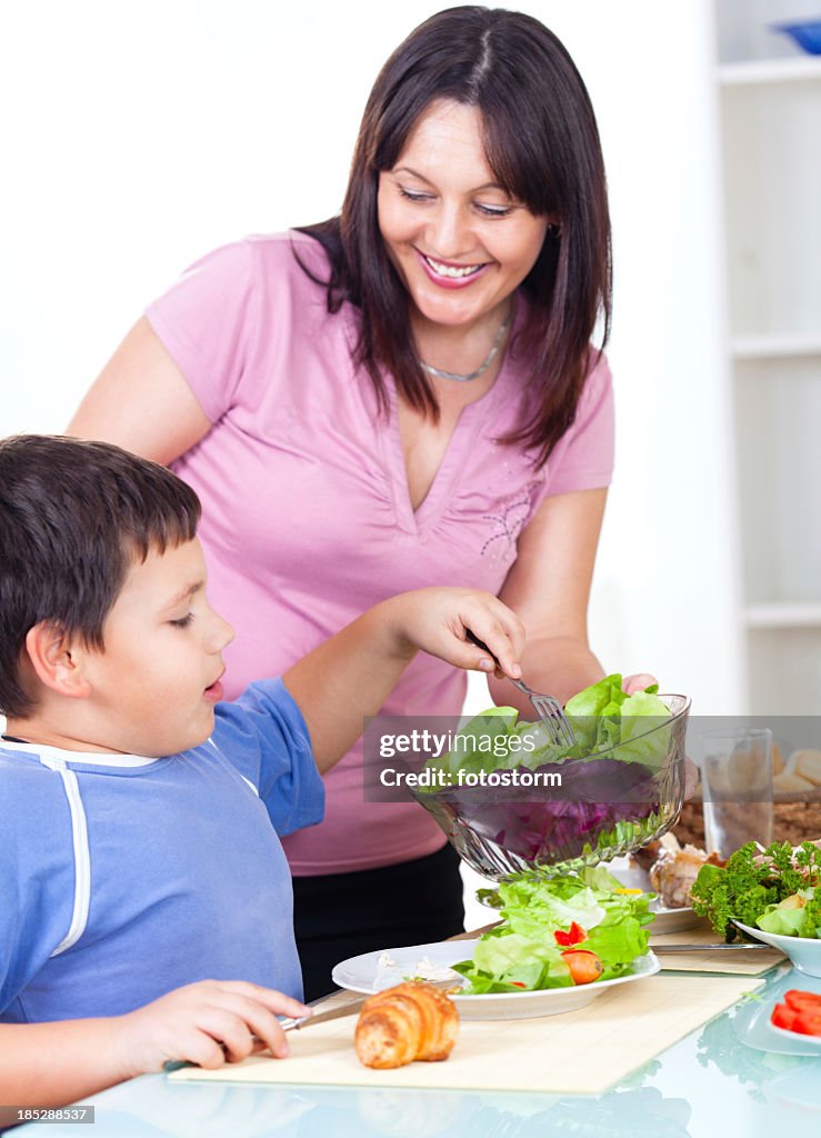 La Madre que sirve frescas ensaladas saludables a su hijo