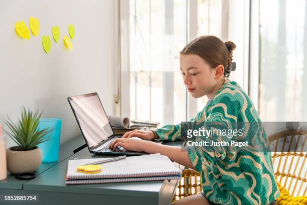 young girl (circa 12 years old) doing her homework from a desk in her bedroom - 12 13 years stock pictures, royalty-free photos & images