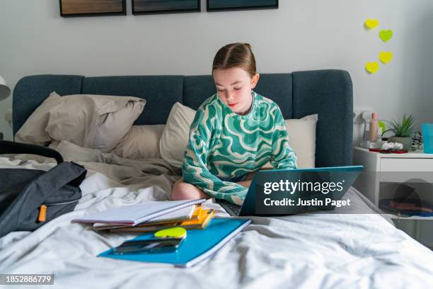 young girl (circa 12 years old) doing her homework from a desk in her bedroom - 12 13 years old girls stock pictures, royalty-free photos & images