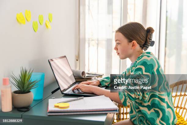 young girl (circa 12 years old) doing her homework from a desk in her bedroom - 12 13 years old girls stock pictures, royalty-free photos & images