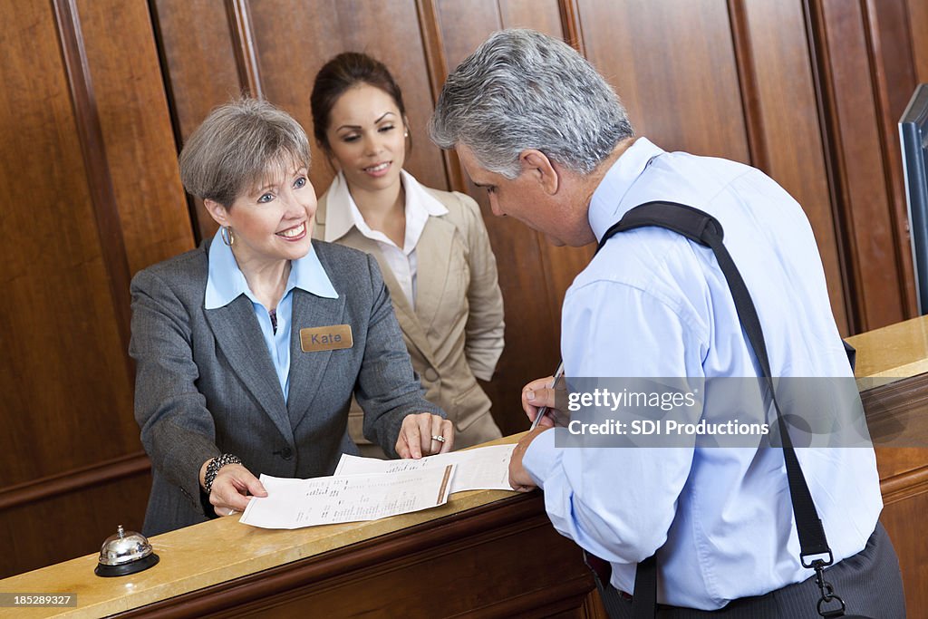 Front desk worker showing hotel bill to guest