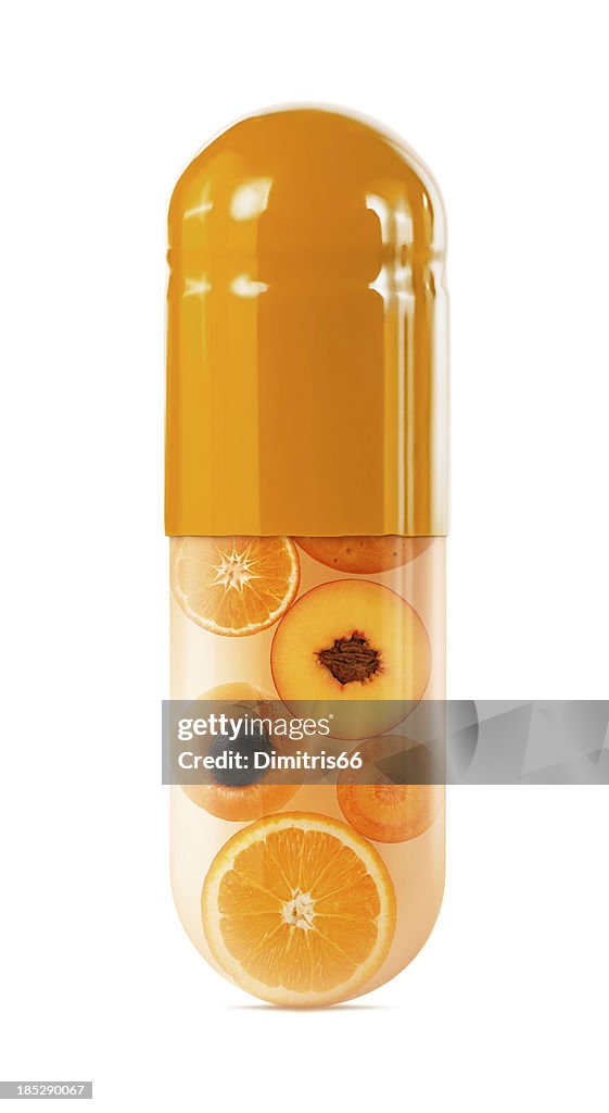 Sliced oranges in oversized capsule on white