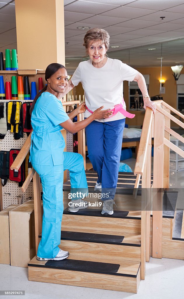 Physical therapist with senior woman climbing stairs