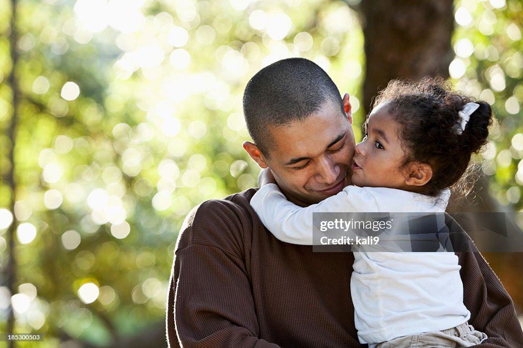 Hispanic father and daughter hugging at park