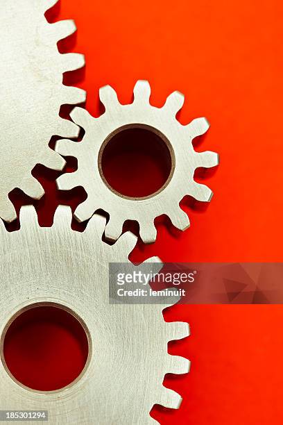 three interlocking gears on red background - red revolution stock pictures, royalty-free photos & images