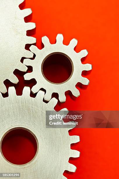três engrenagens interlocking sobre fundo vermelho - roda dentada imagens e fotografias de stock
