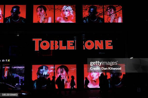 Members of the public walk past an advertising display on Oxford Street on December 13, 2023 in London, England.