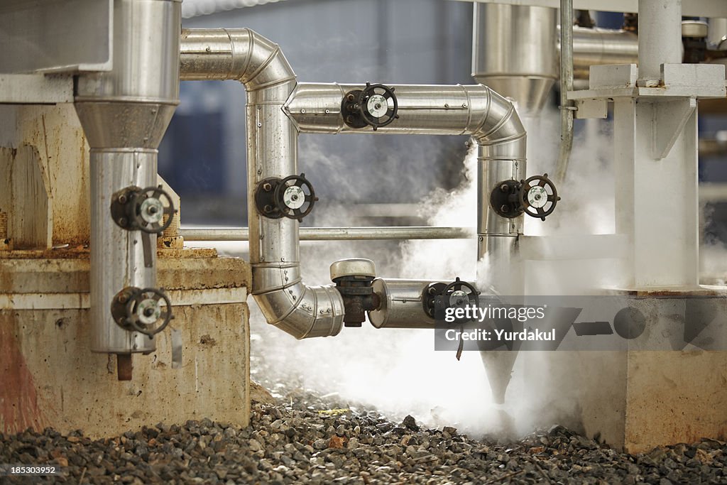 Pipelines emitting steam at industrial site