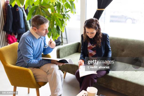 two business people discussing over some documents in a meeting at office lobby - lobby stock pictures, royalty-free photos & images