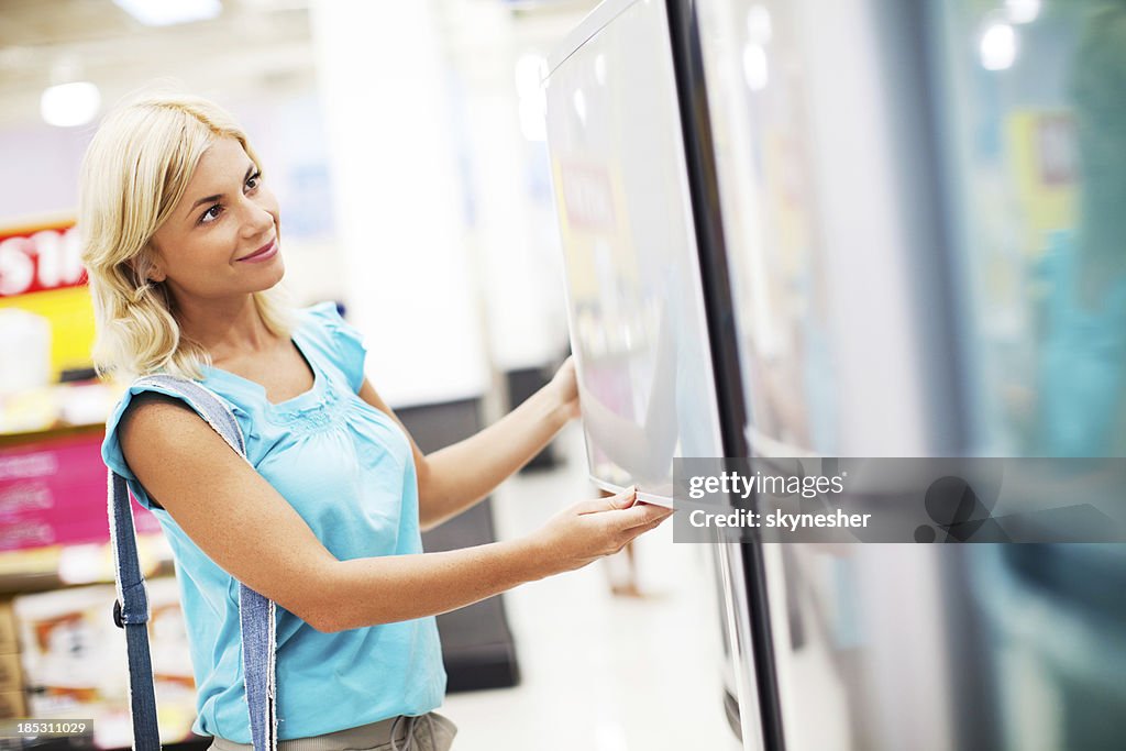 Mulher em uma loja comprar frigorífico.