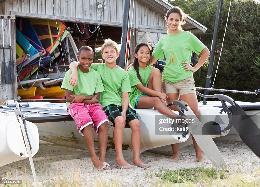 Teenager and children in front of water sports equipment shack