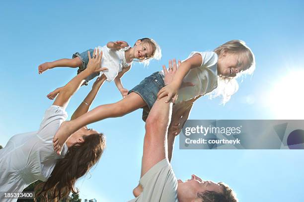 parents joyfully throwing their children in the air. - girls wrestling stockfoto's en -beelden