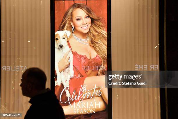 Man walks in front of a Mariah Carey poster in the window of American lingerie chain Victoria's Secret during the holiday shopping season on December...