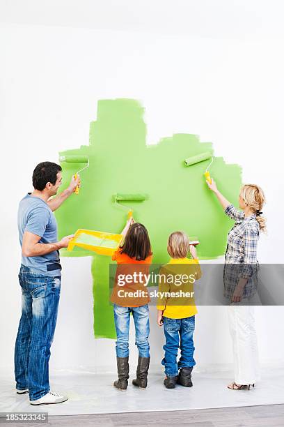 family painting the wall. - holding paint roller stock pictures, royalty-free photos & images