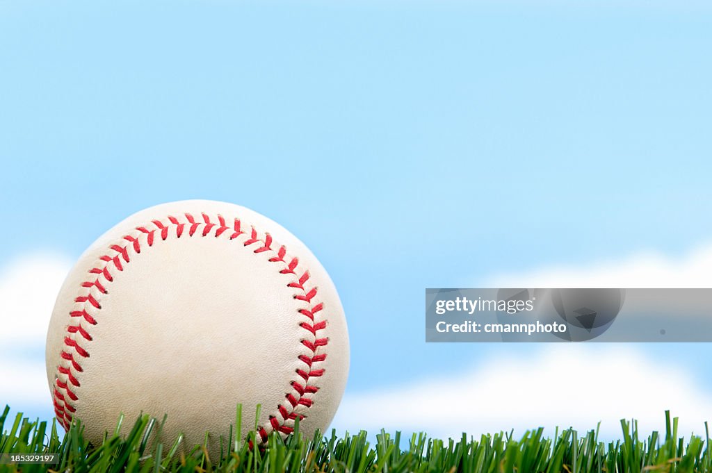 New Baseball in Grass against blue sky