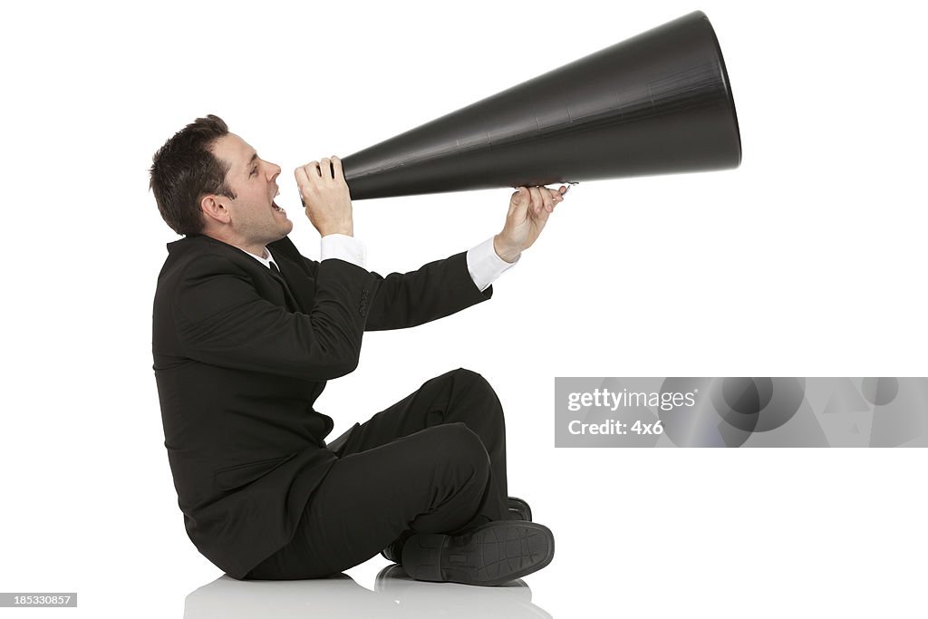 Homem de negócios a gritar dentro de um Alto-falante Portátil