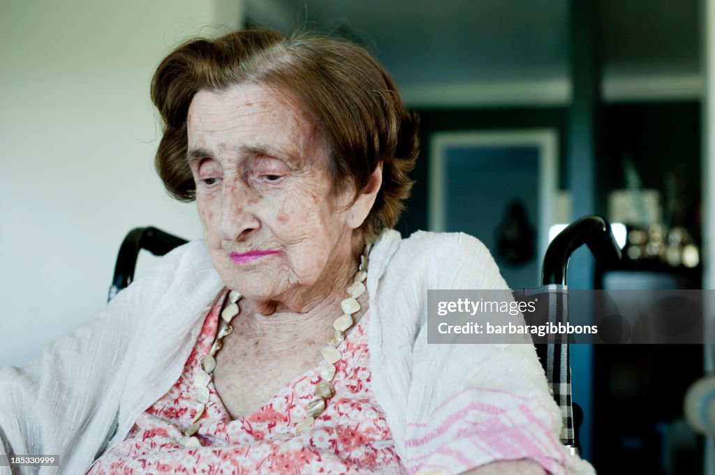 Portrait of an elderly woman in a wheelchair looking down 