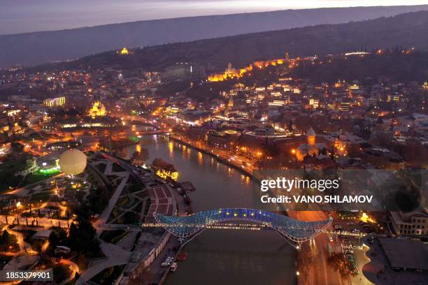 This aerial view taken in Tbilisi on December 16, 2023 shows the Bridge of Peace illuminated with EU flag to mark the Georgia's European Union...