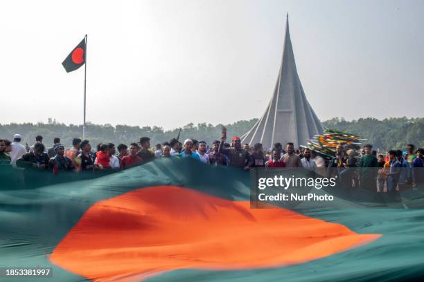 People are waving national flags as they gather to pay their respects at the 1971 Independence War's Martyrs National Memorial to celebrate the 52nd...