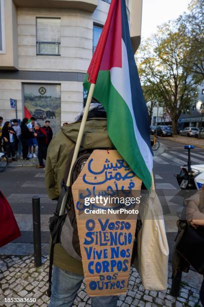 An activist is carrying a flag and a banner calling for an end to war and hostilities in Gaza during a demonstration near the Israeli embassy in...