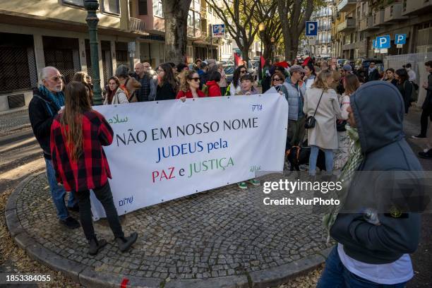 Activists are carrying a banner calling for a ceasefire in the Gaza Strip as they hold a rally in front of the Israeli embassy facilities in Lisbon,...