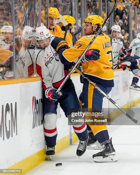 Jeremy Lauzon of the Nashville Predators checks Connor McMichael of the Washington Capitals during an NHL game at Bridgestone Arena on December 16,...